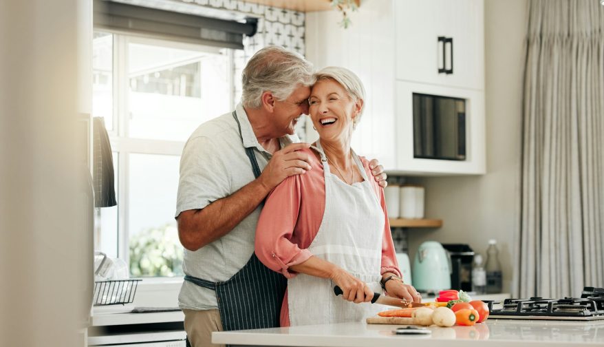 Senior couple in kitchen, cooking healthy food together and happy in retirement lifestyle. Elderly